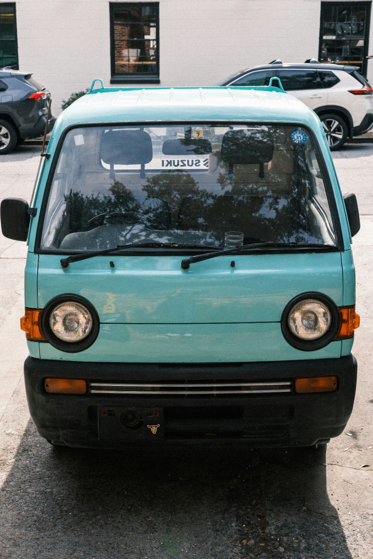 Teal Suzuki Carry Kei van parked on a street, enclosed, lockable, camper-ready